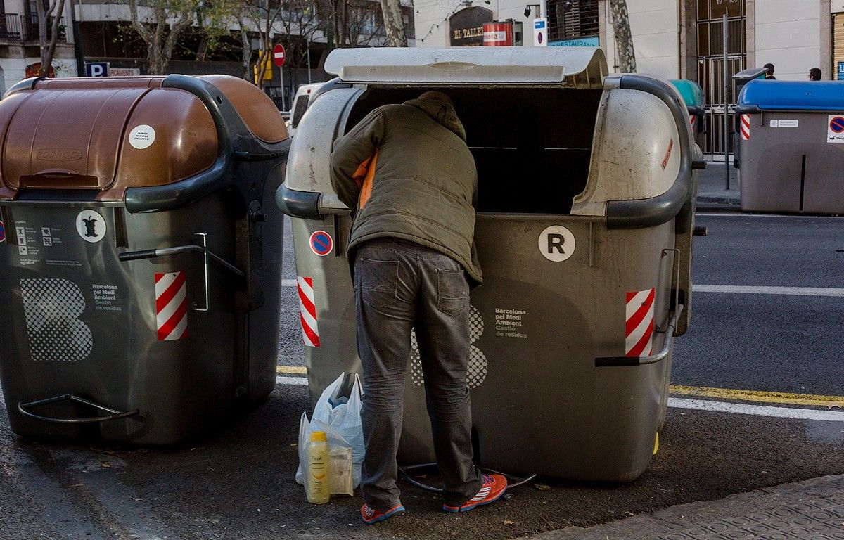 Un home rebusca en un contenidor, a Barcelona.