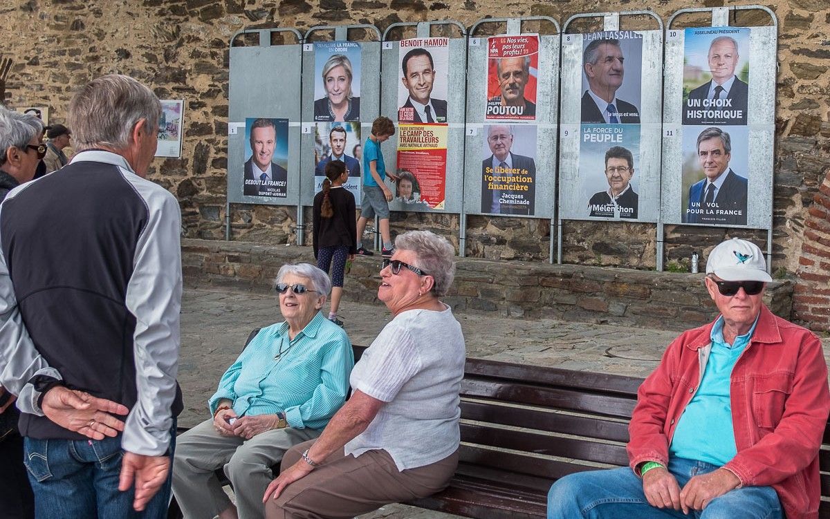 Gent gran xerrant a Cotlliure a tocar d'uns cartells de les presidencials franceses