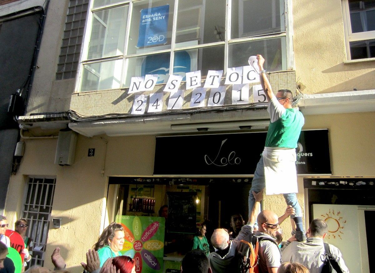 Membres de la PAHC penjant cartells a la façana de la seu del PP de Sabadell