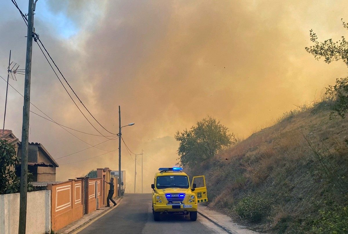 Els ADF evacuant persones de diverses cases amb una columna de fum de fons