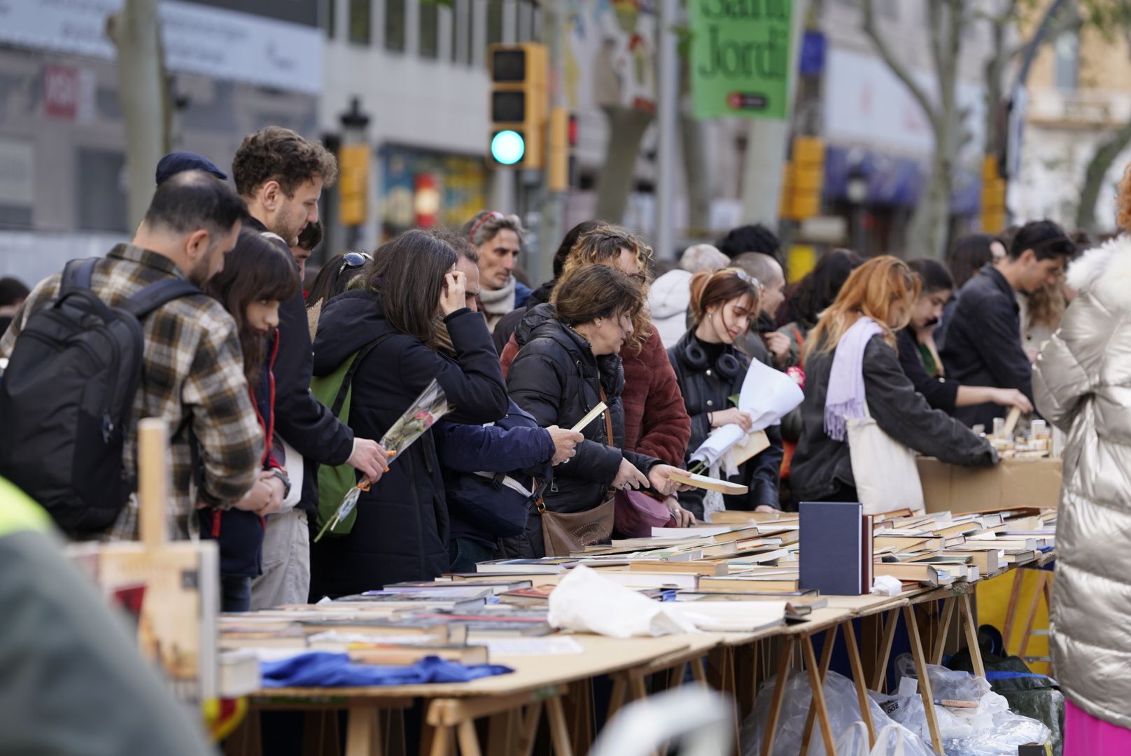 Un grup de persones remena llibres en una parada de Sant Jordi a Barcelona