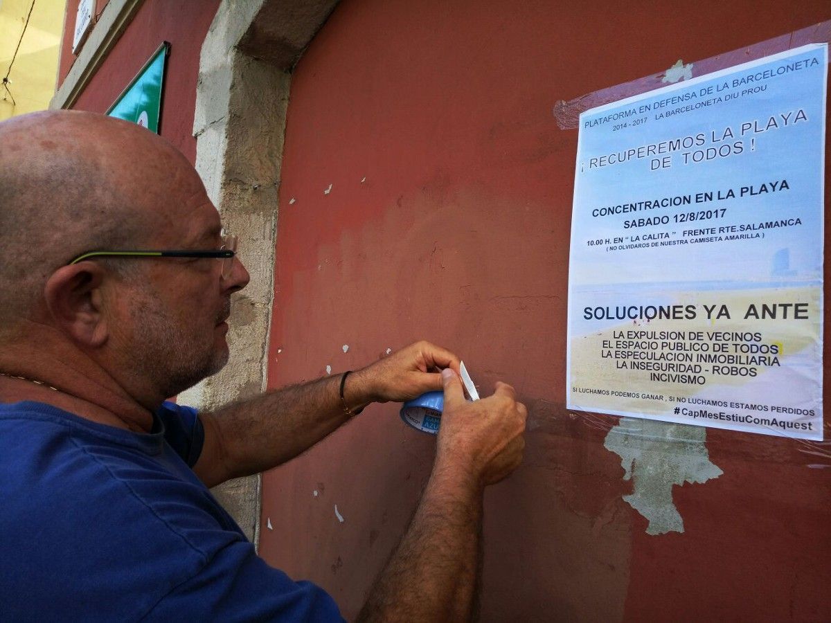 Sebas, un veí i activista de la Barceloneta, penja un cartell de la manifestació.