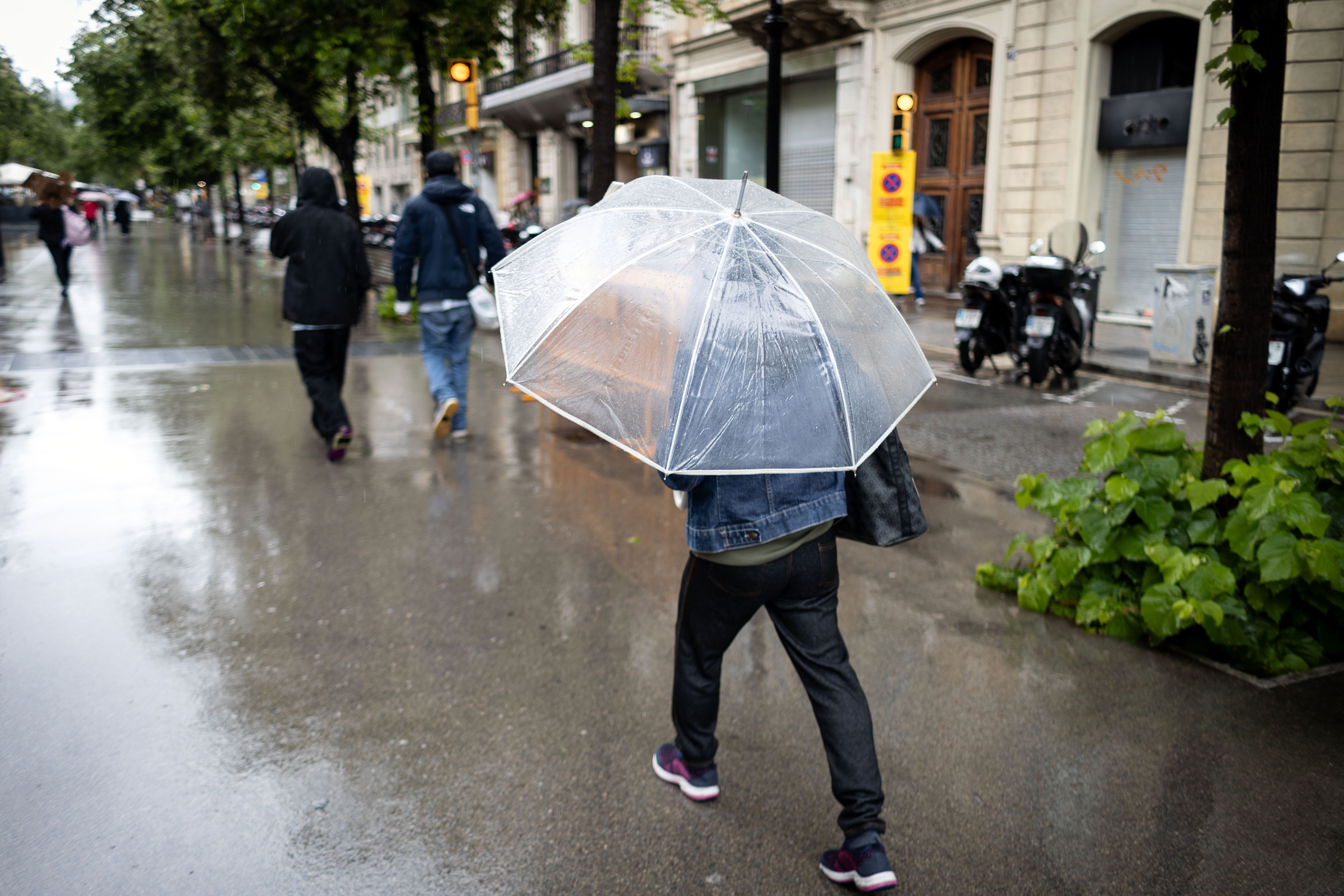 Transeünts es protegeixen de la pluja al centre de Barcelona