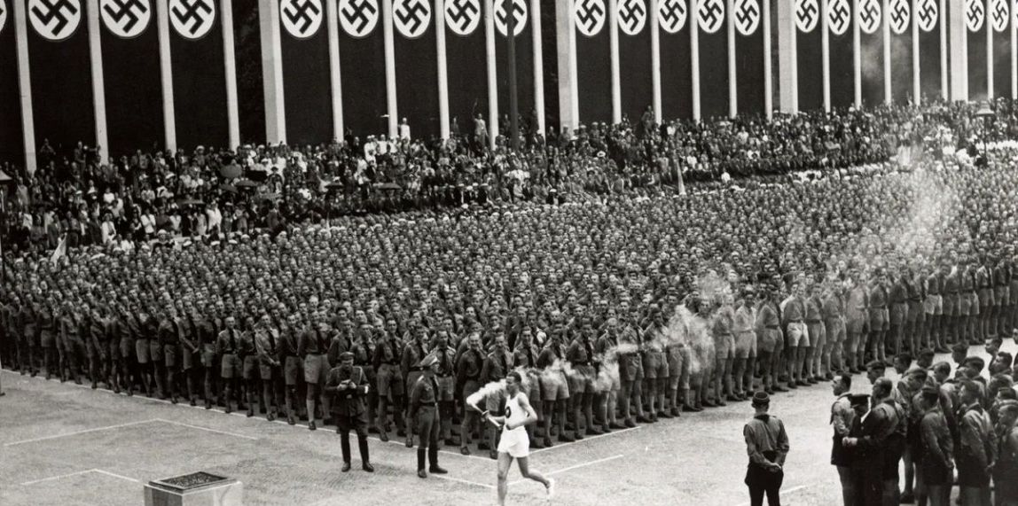 La torxa olímpica arriba a un estadi Olímpic de Berlín completament engalanat amb símbols nazis durant la cerimònia inaugural dels Jocs de 1936