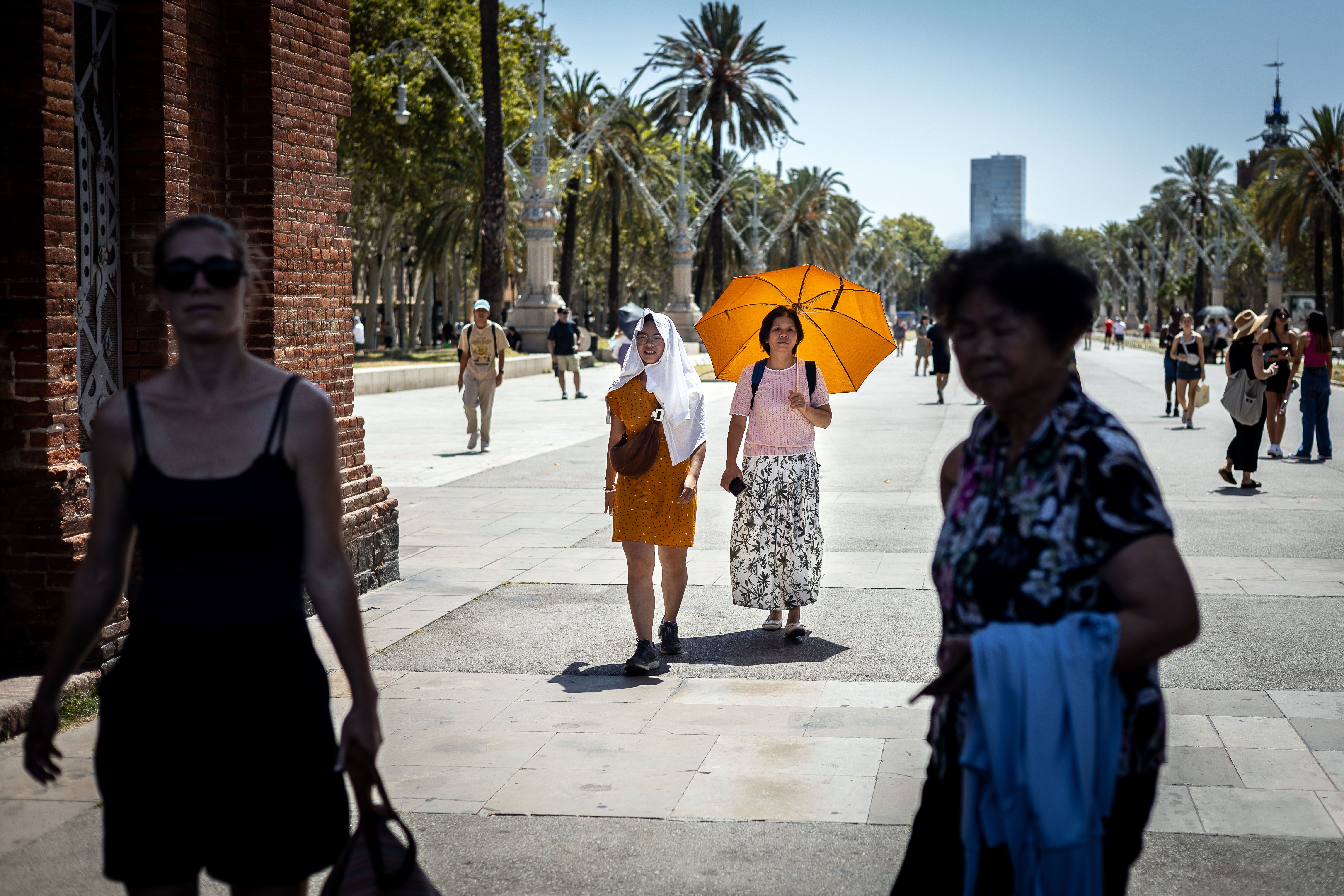 Uns turistes s'amaguen del sol al Passeig Lluís Compnays de Barcelona, ​​durant l'onada de calor