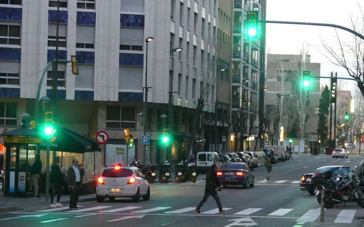 Una persona travessant per l'avinguda Prat de la Riba quan el semàfor per a vehicles està en verd