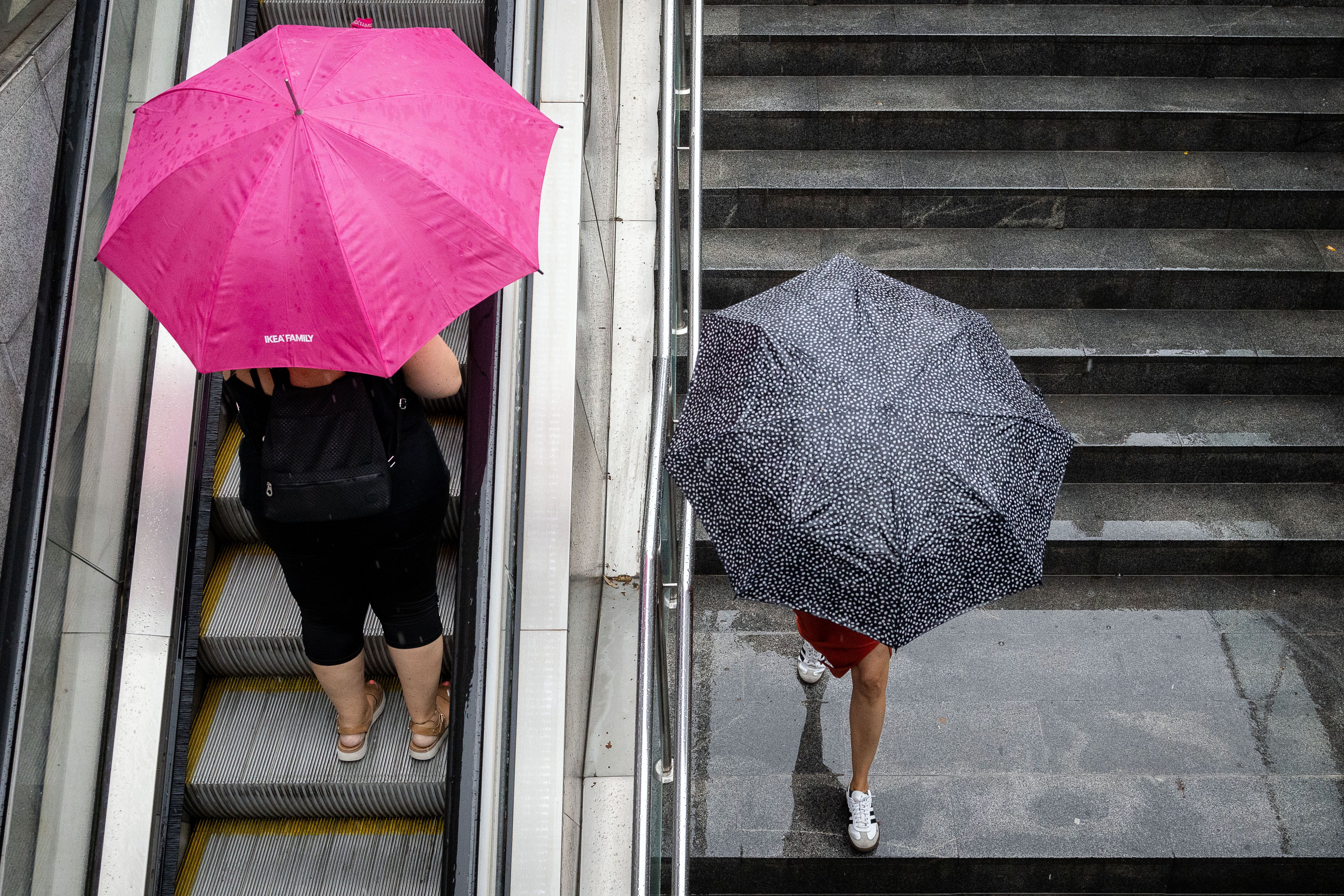 Dues persones es refugien de la pluja al metro de Barcelona