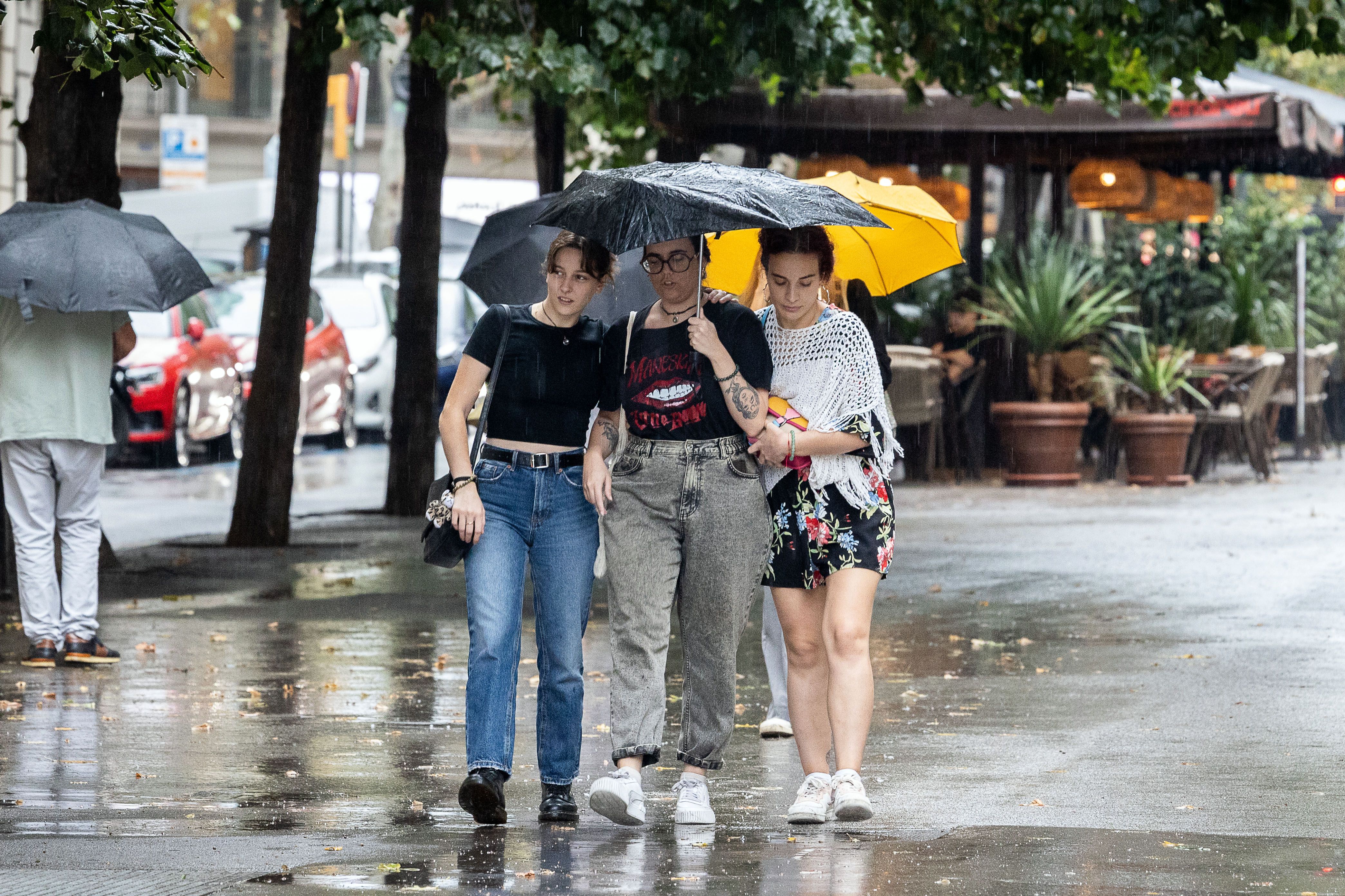 Diverses joves es refugien de la pluja al centre de Barcelona