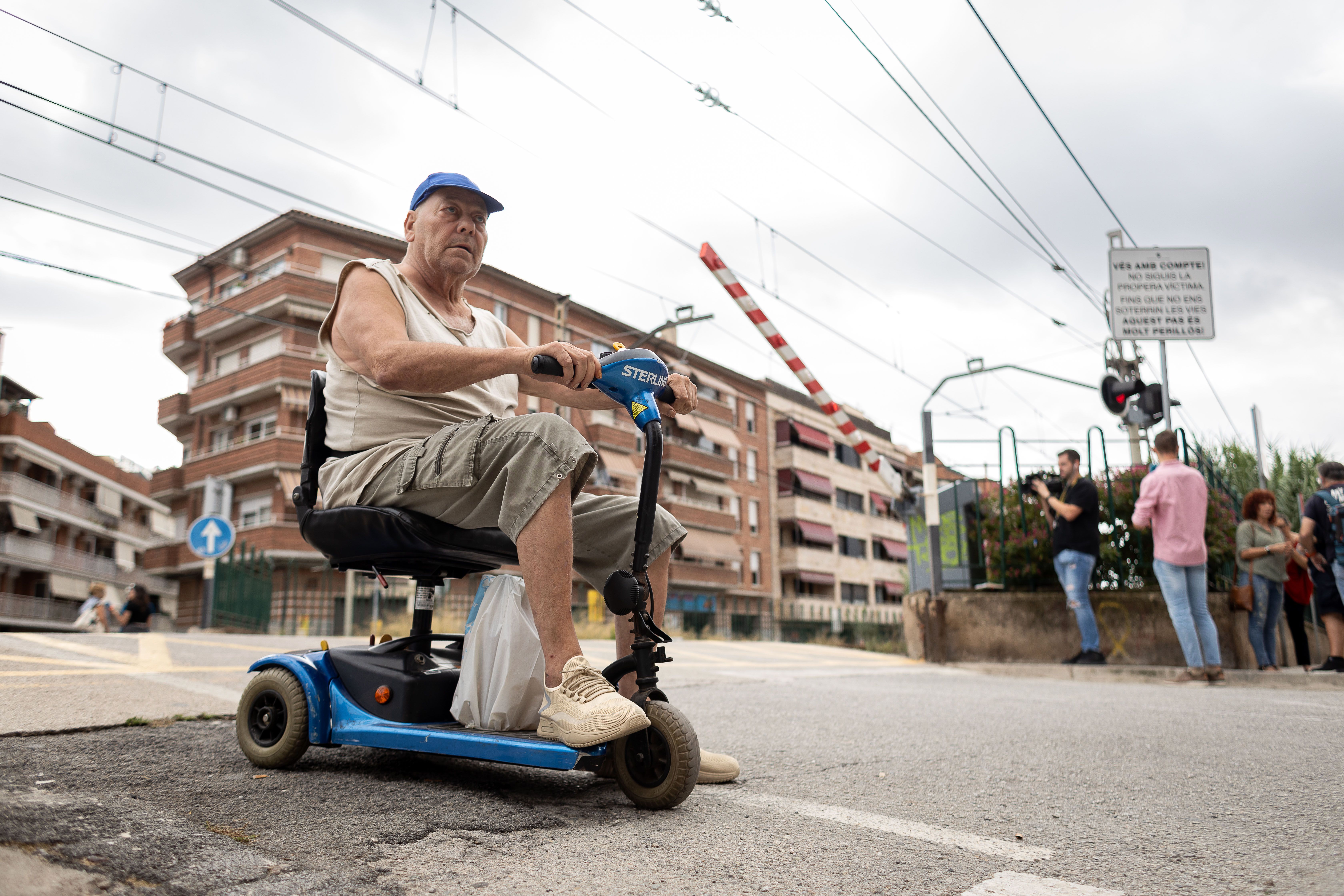 Un veí amb mobilitat reduïda creuant les vies del pas de l'R2