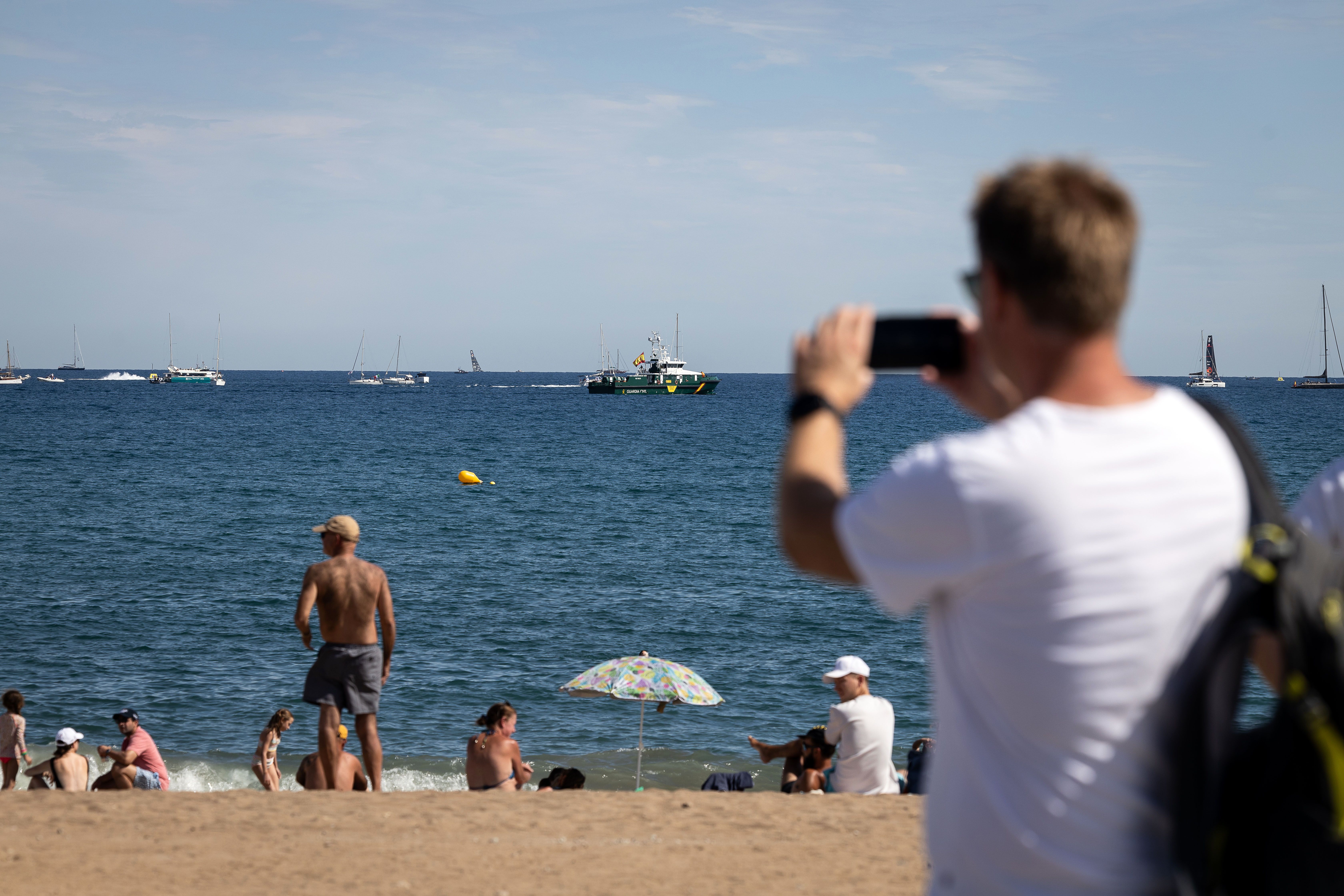 Un turista fotografia el mar, amb els vaixells de la Copa Amèrica de fons