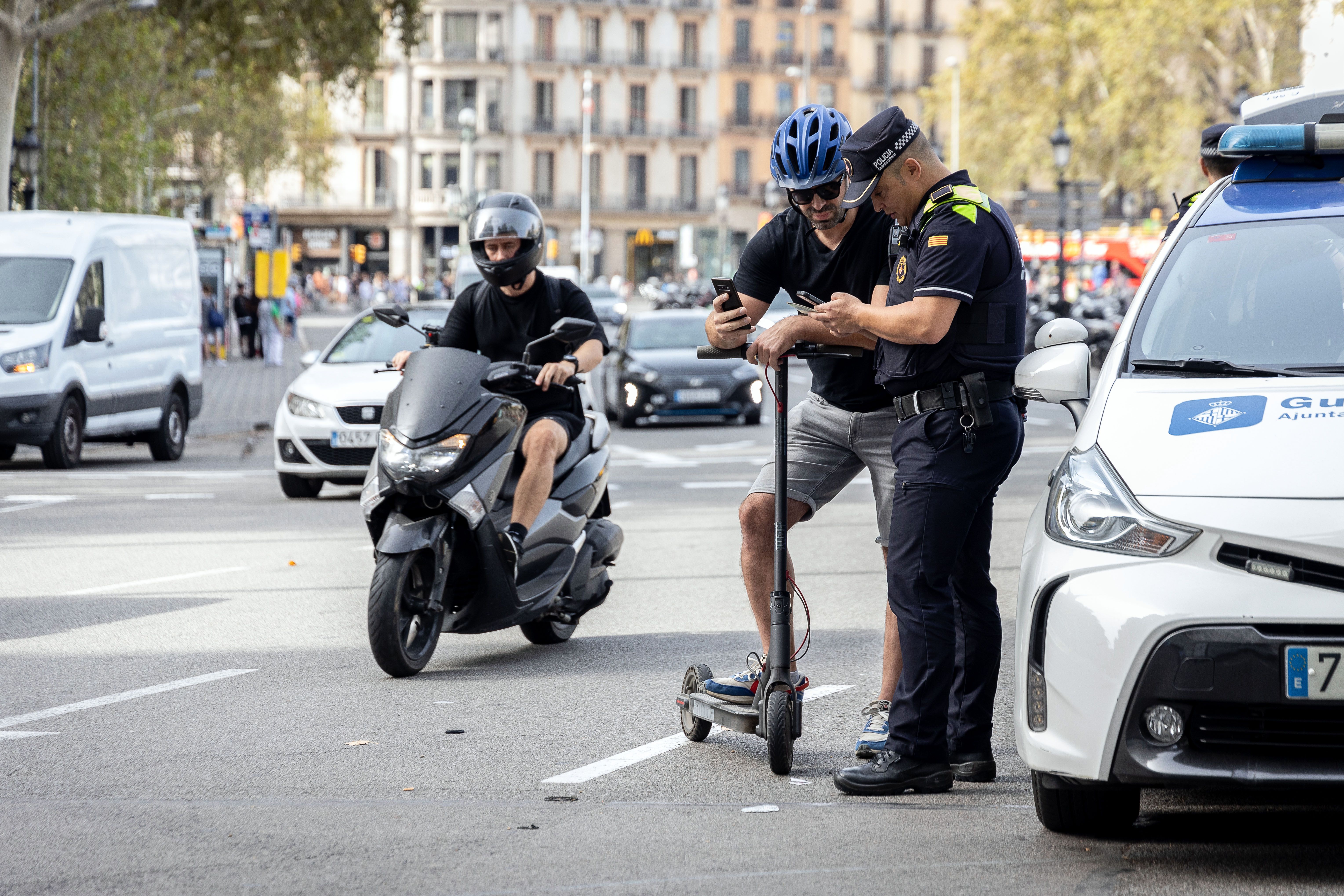 Un policia atura un conductor de patinet elèctric, en imatge d'arxiu