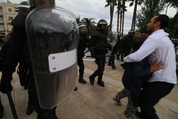 Dues persones abraçant-se enmig d'antiavalots de la policia espanyola