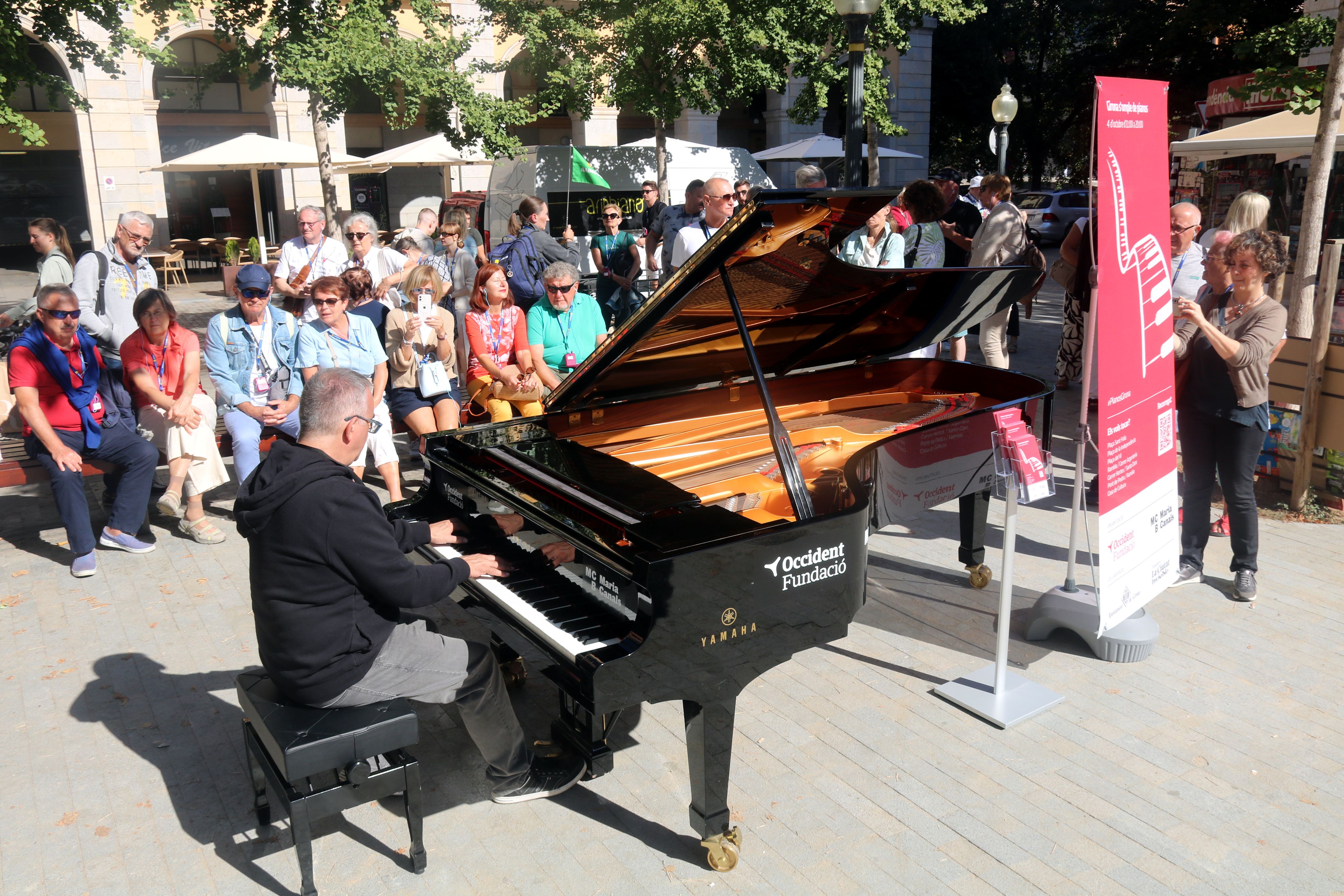 Un home toca un dels dos pianos de gran cua que s'han repartit pel centre de Girona, en concret a la plaça de la Independència