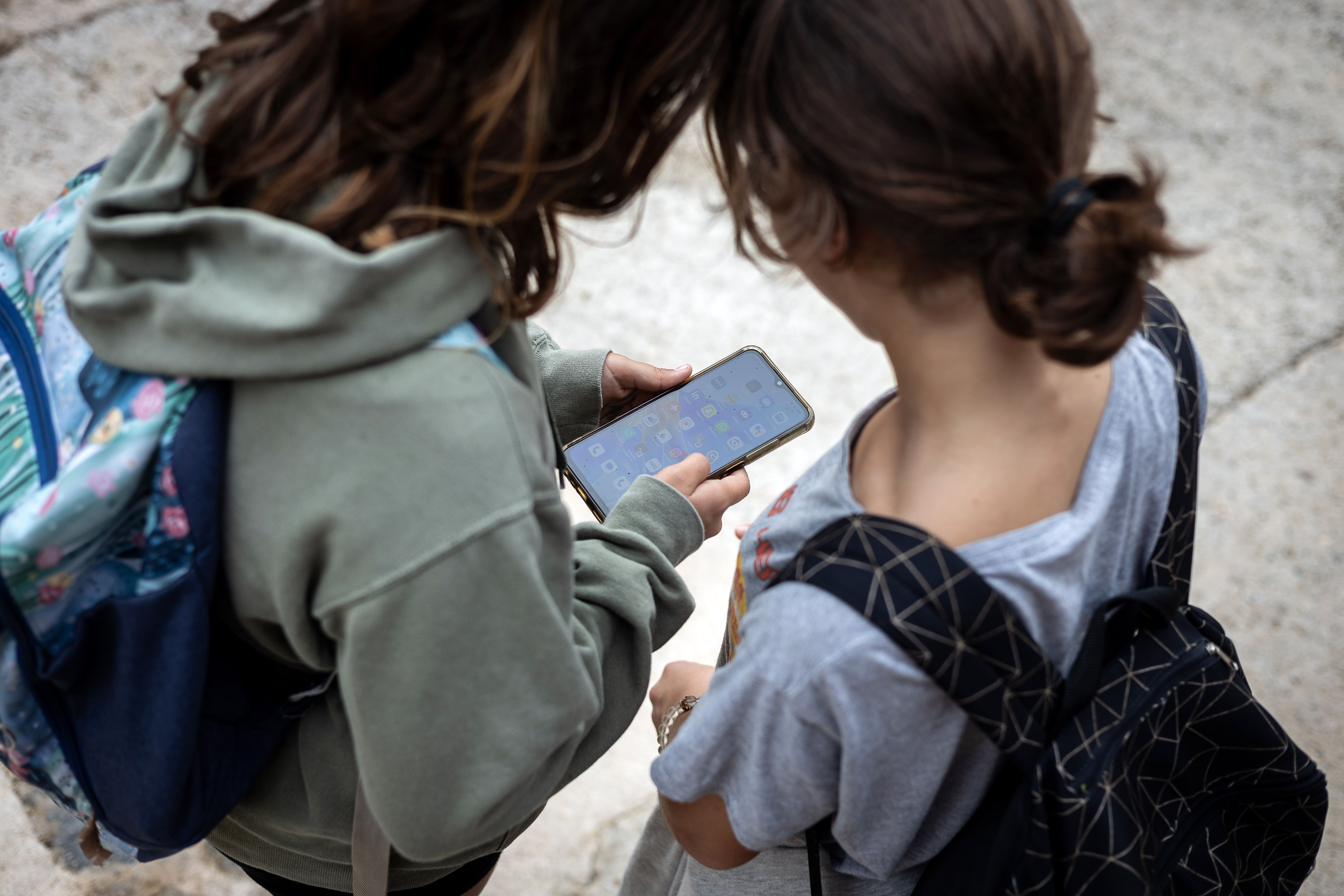 Dos infants utilitzen el mòbil desprès de l'escola