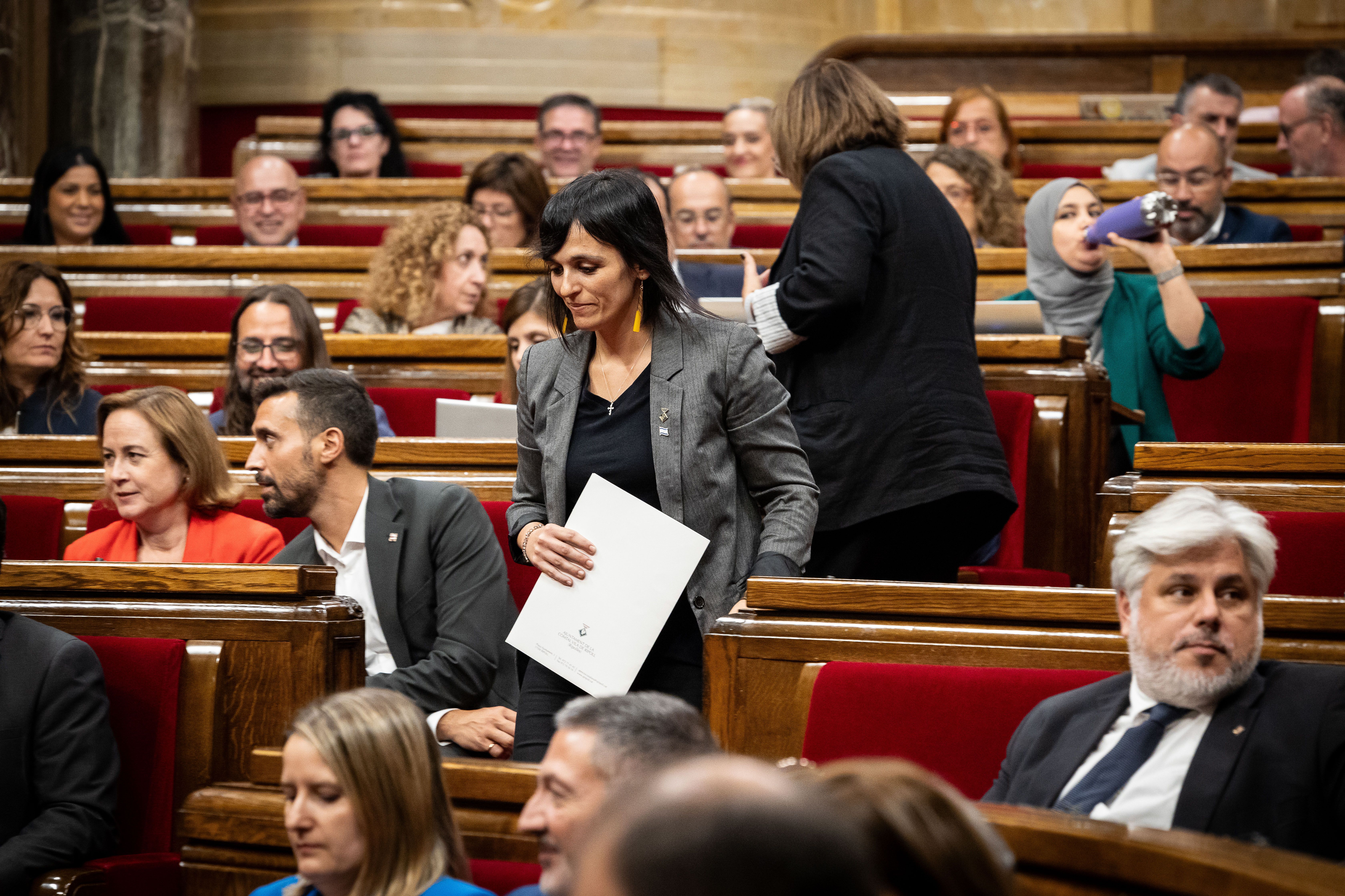 Sílvia Orriols baixa les escales de l'hemicicle mentre Albert Batet, de Junts, mira cap a una altra banda.