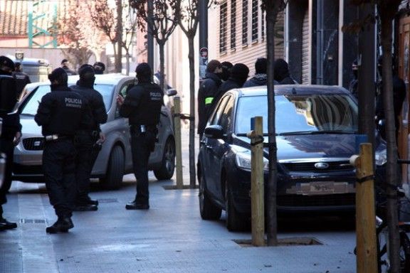 Els agents dels Mossos d'Esquadra al costat de vehicles policials camuflats al carrer on es troba situat l'Ateneu Llibertari de Sants