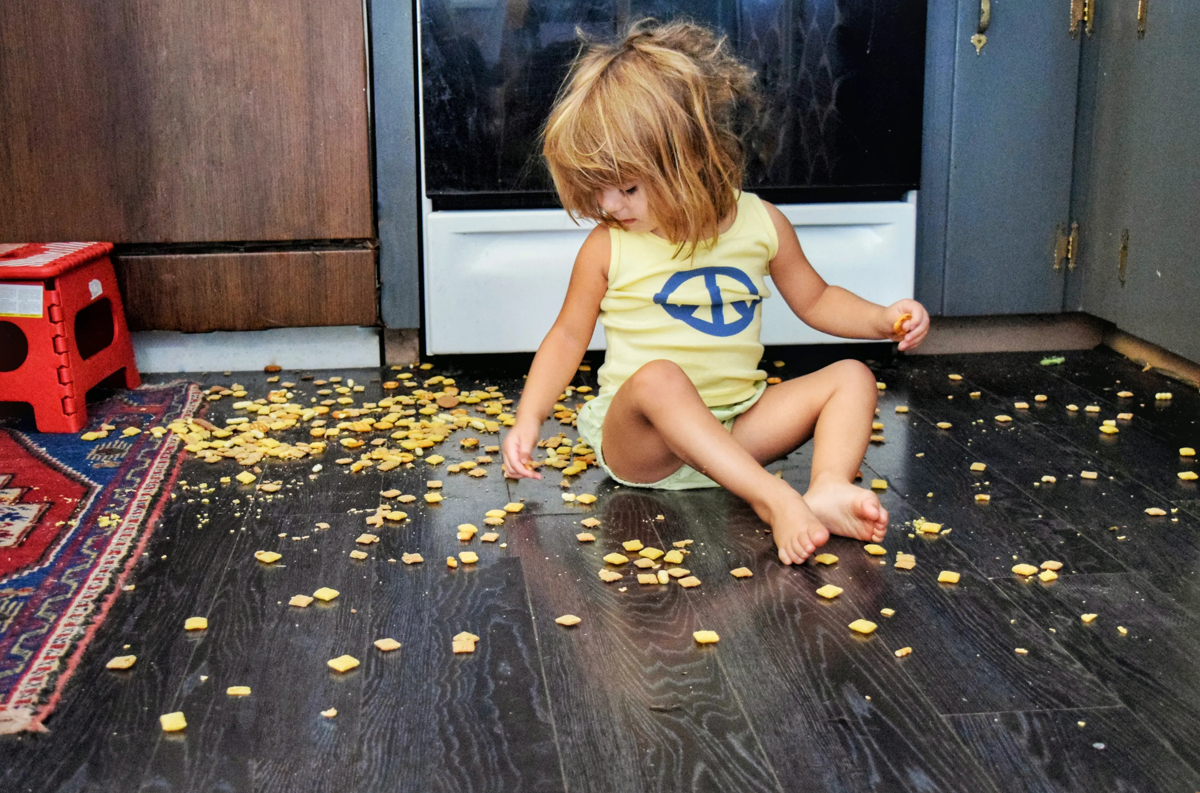 Una nena menja cereals que li han caigut a terra