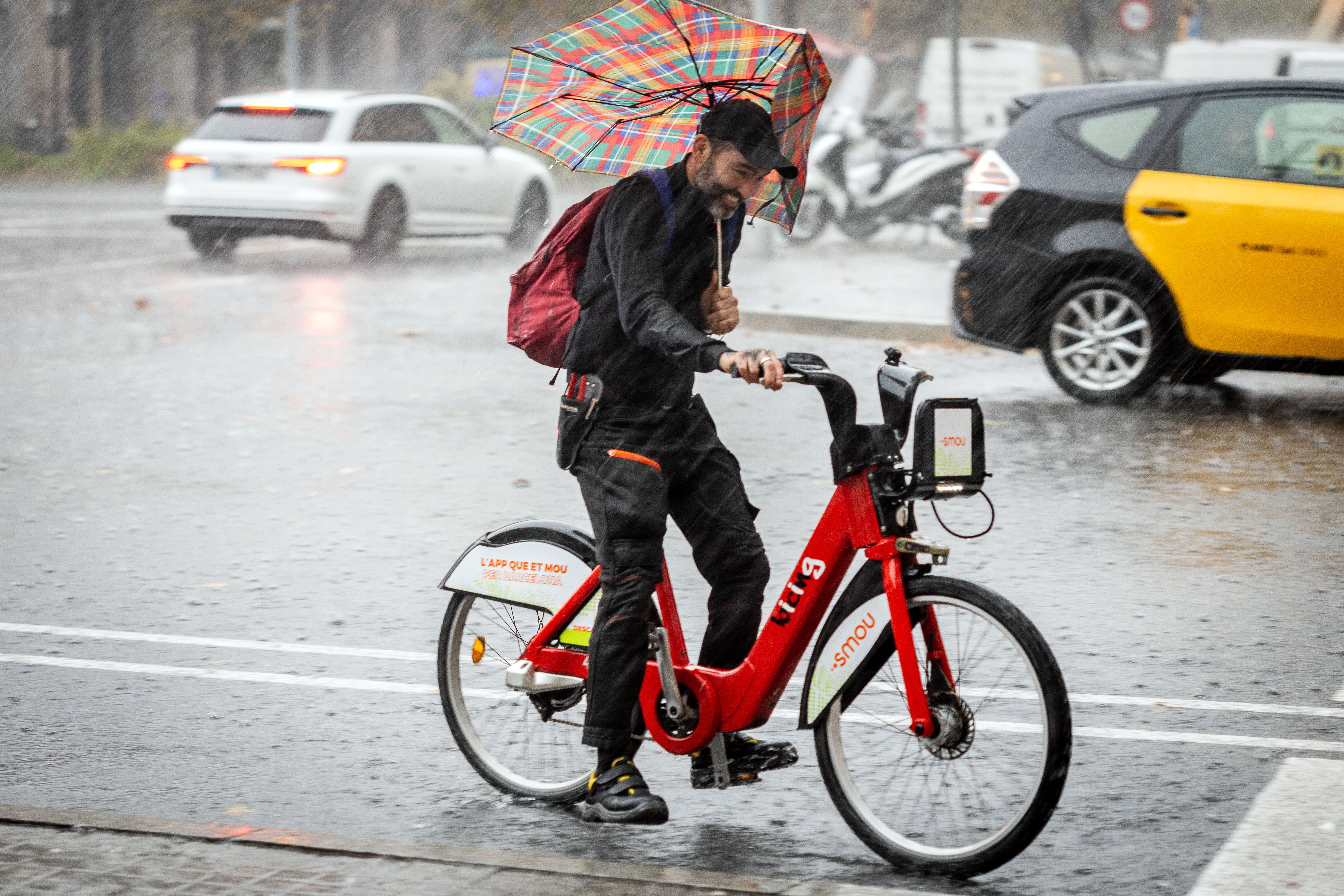 Un home pateix per la pluja a Barcelona