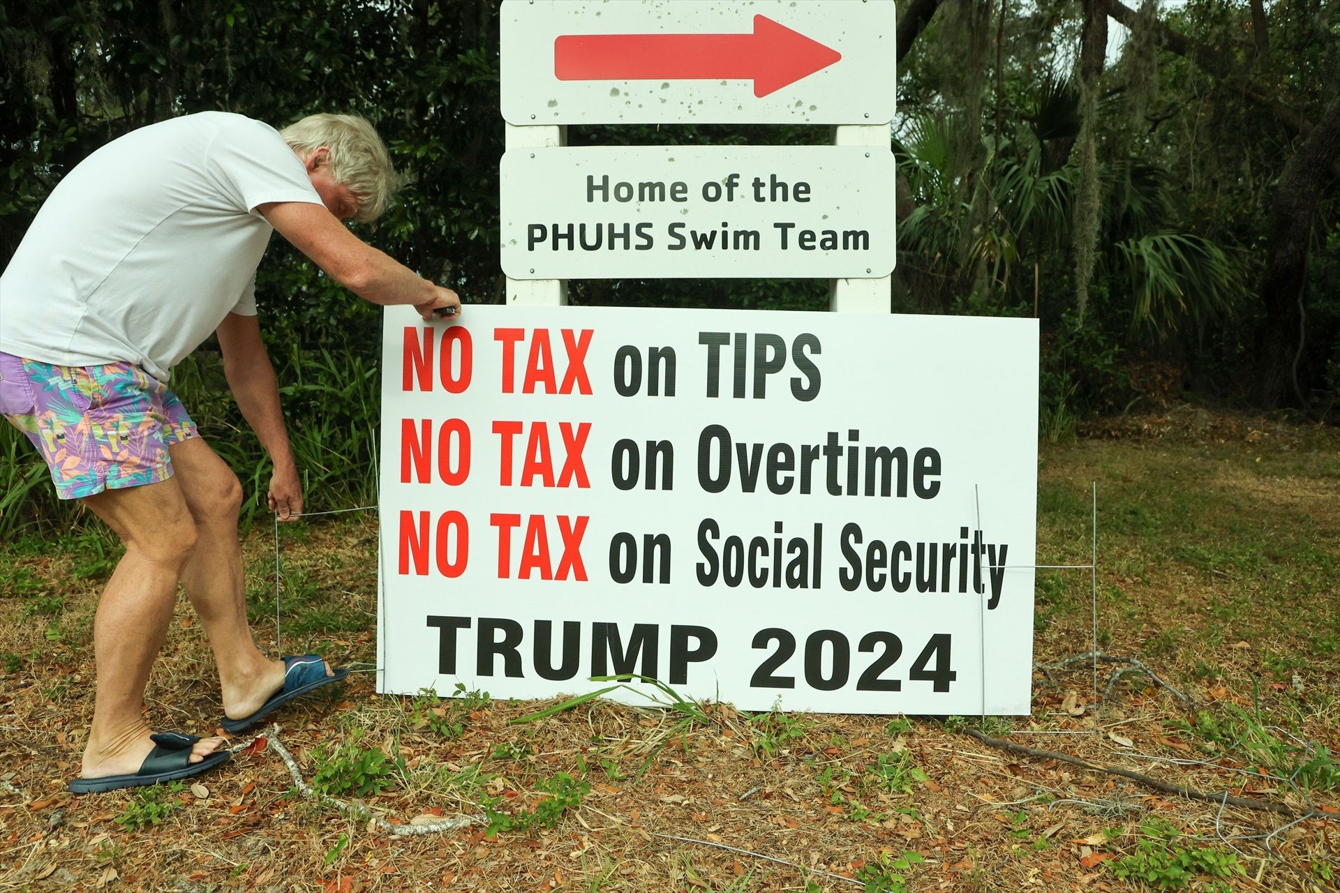 Un home planta un cartell a favor de Trump a Palm Harbor, en plena jornada electoral