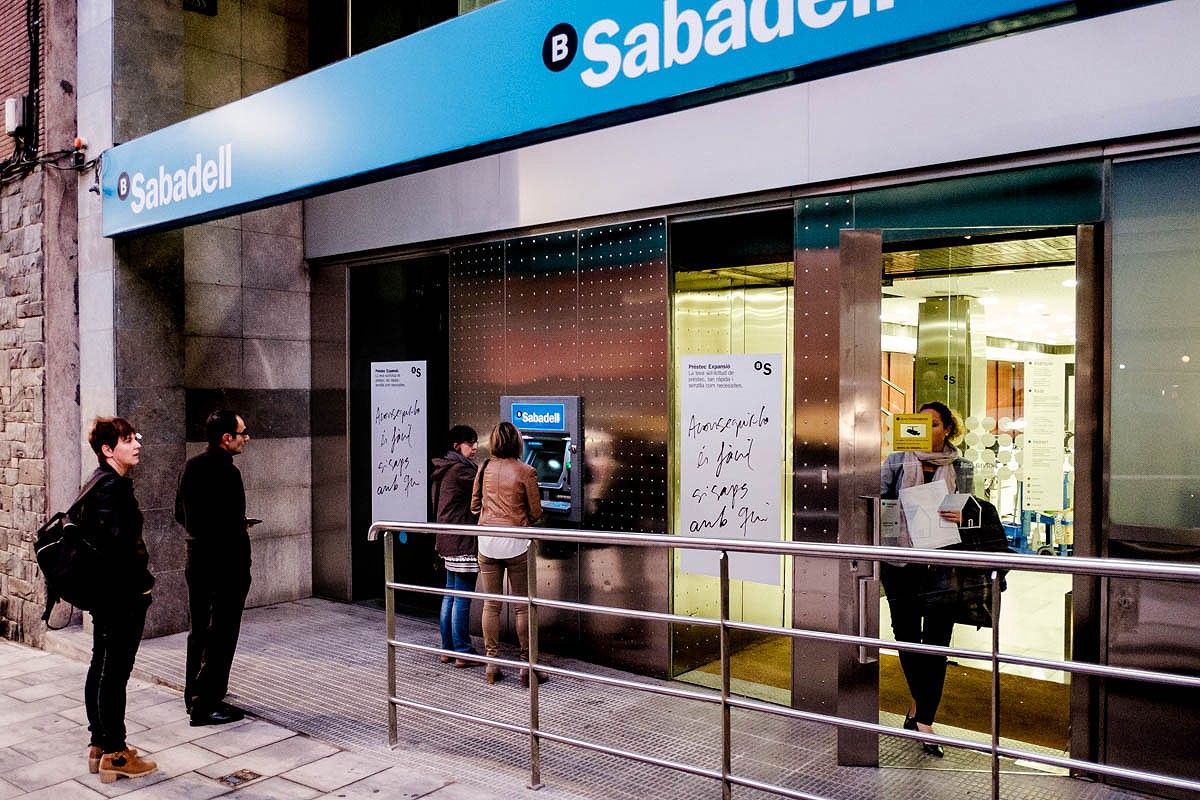 Diverses persones fan cua a una oficina del Banc Sabadell de Vic