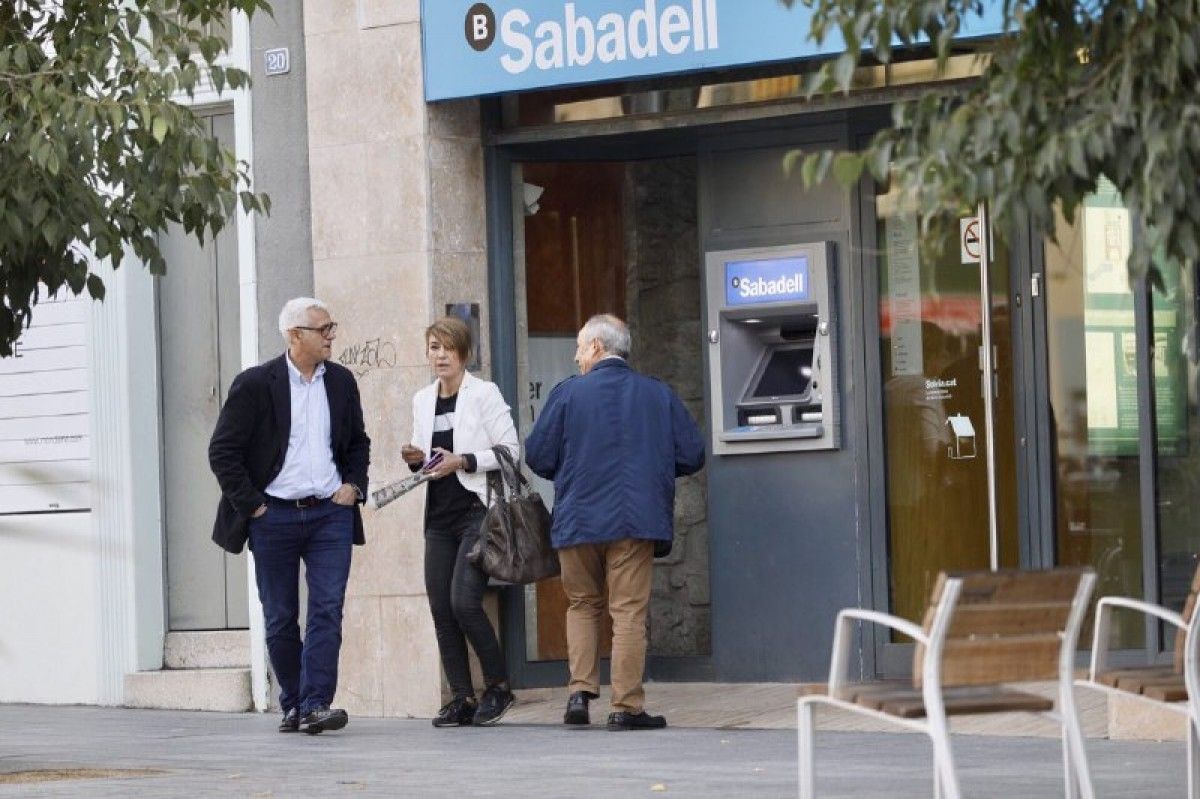 Gent retirant diners d'un caixer de Banc Sabadell.