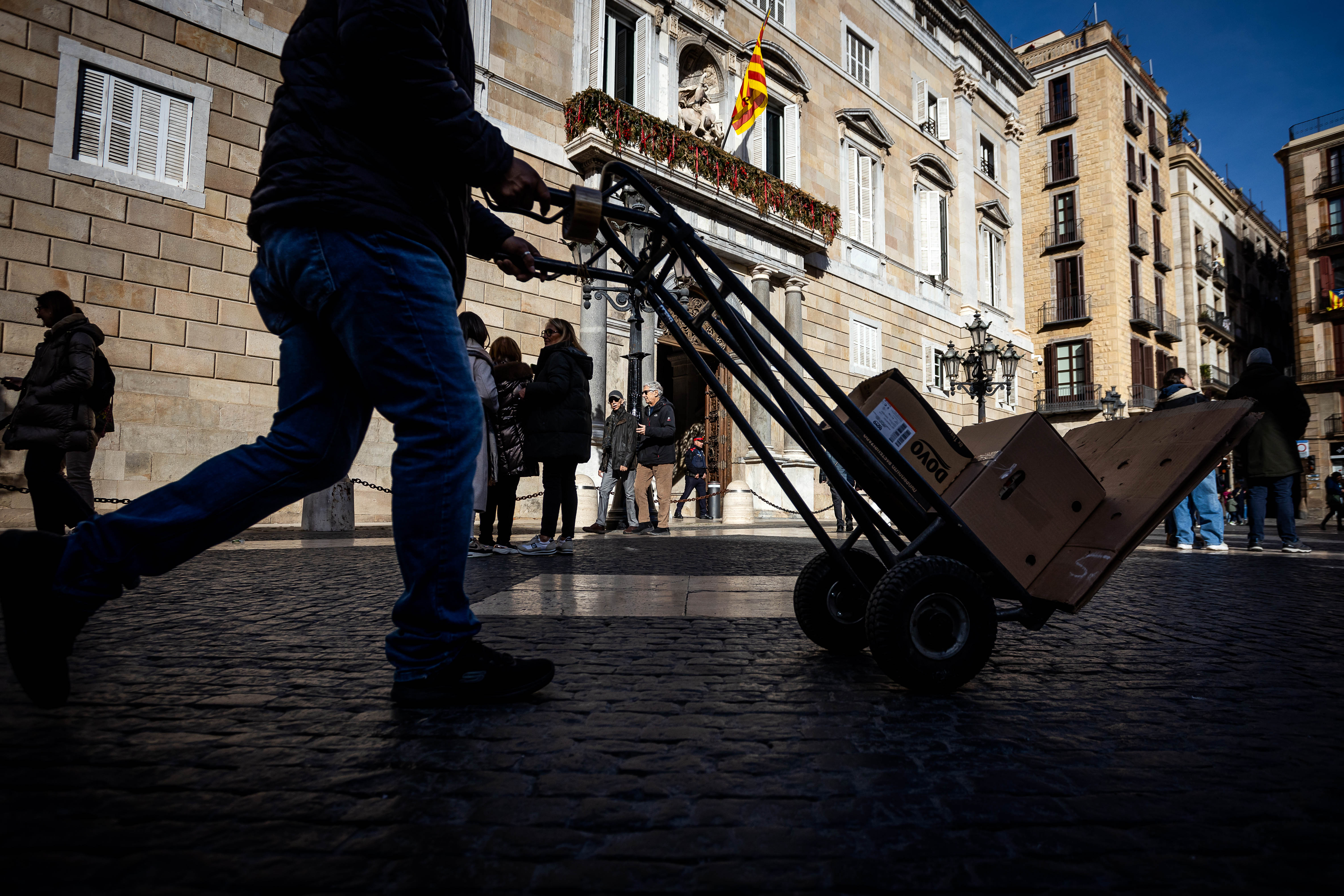 Un repartidor carregant paquets davant del Palau de la Generalitat, a la Plaça Sant Jaume de Barcelona.