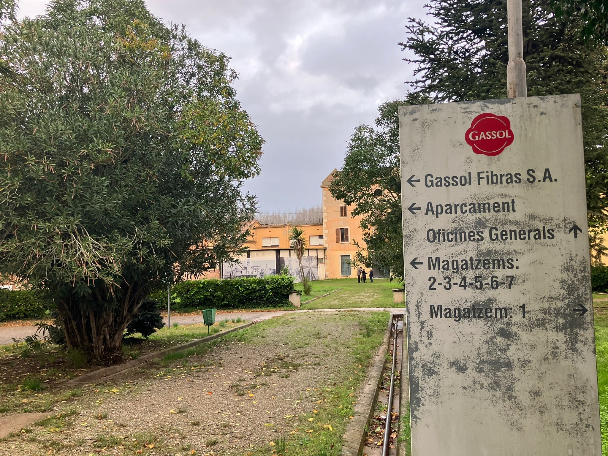 Entrada a l'antiga fàbrica Gassol de Salt amb un cartell en primer terme que indica alguns dels espais que tenia la indústria