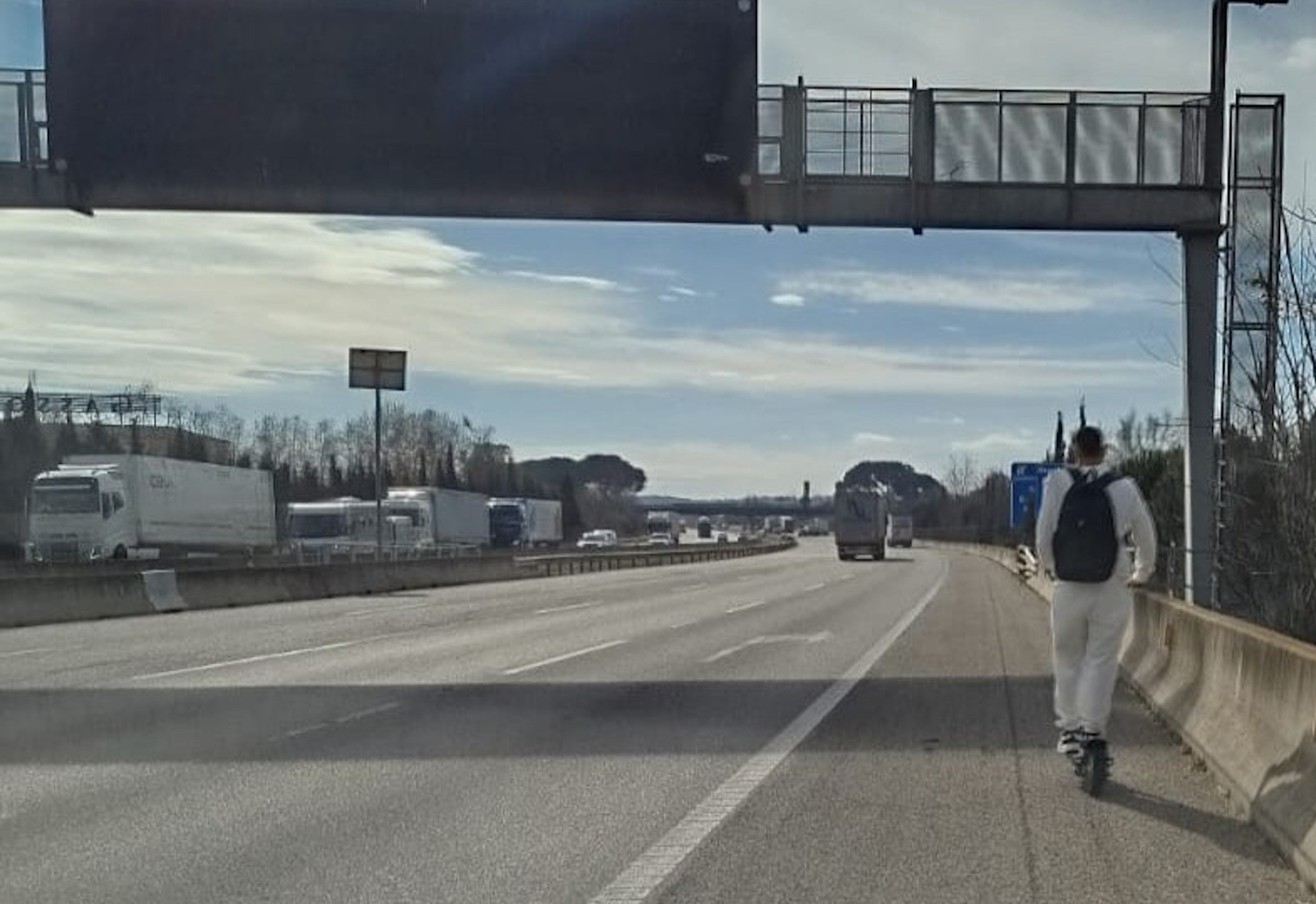 Imatge del noi conduint un patinet elèctric per l'autopista.