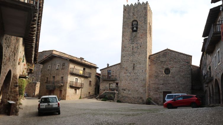 La plaça Major de Santa Pau, zona restringida a vehicles, amb alguns cotxes aparcats