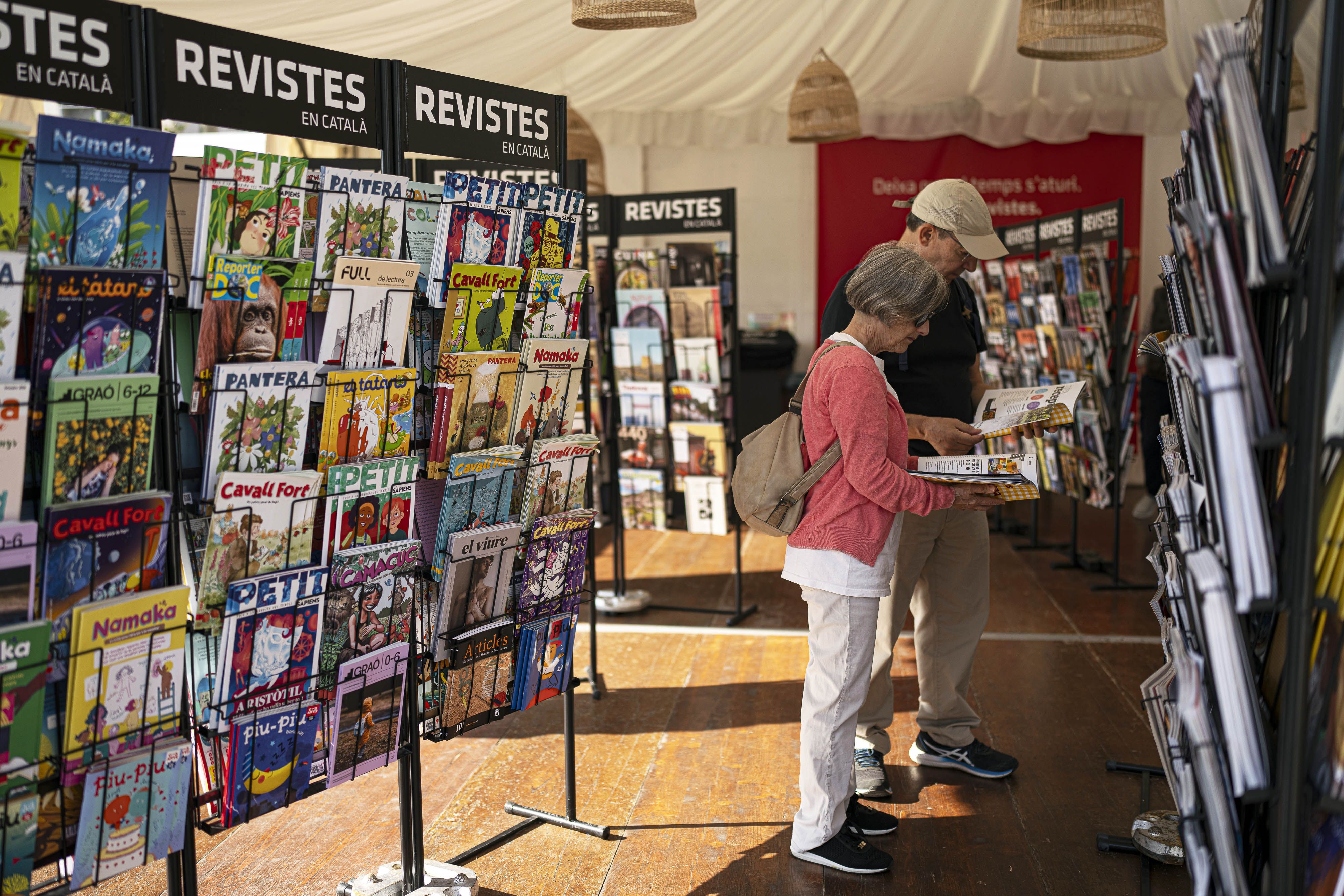 Dues persones consultes revistes a la Setmana del Llibre en Català.