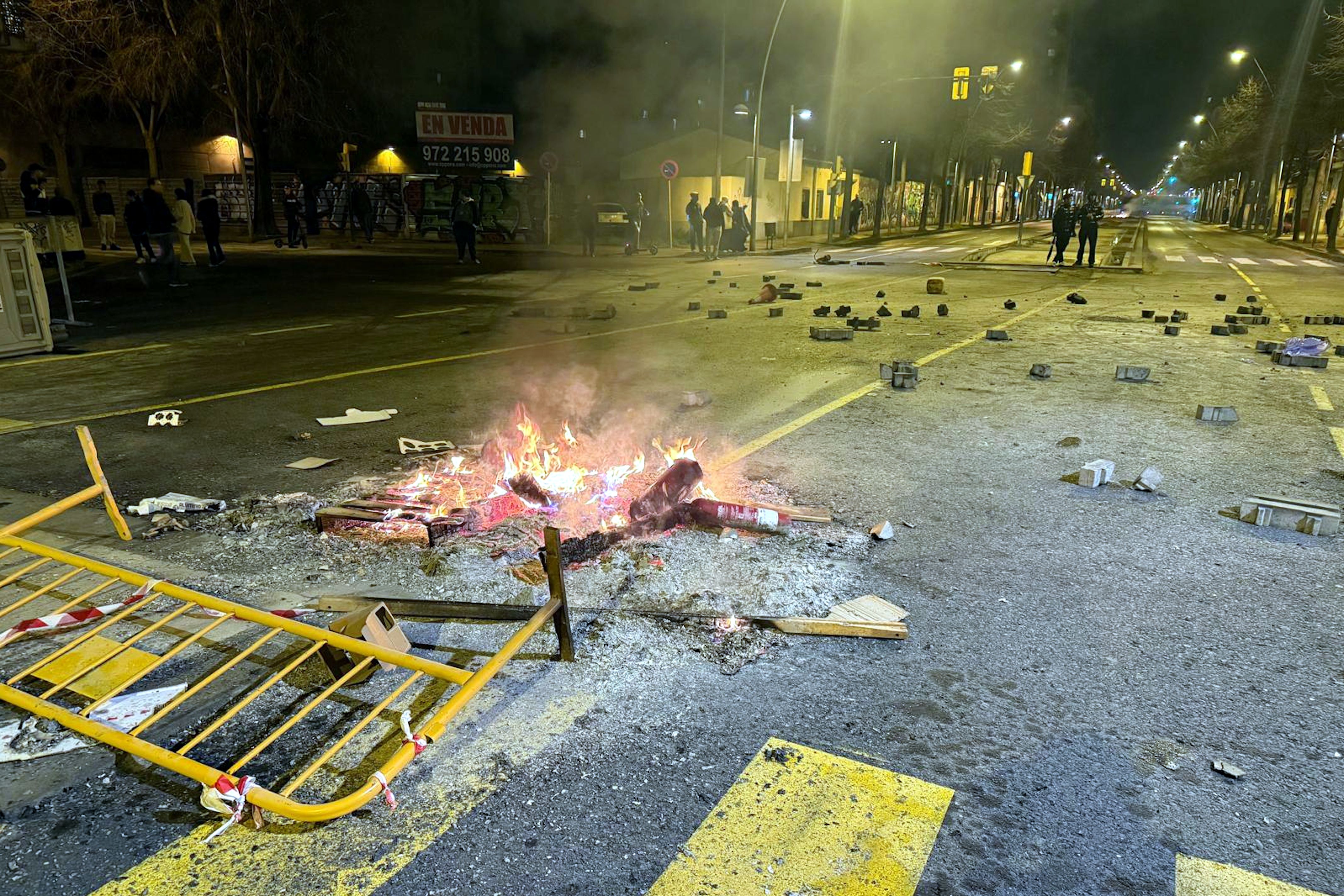 El passeig dels Països Catalans de Salt amb pedres a la calçada i una foguera fumejant arran dels aldarull