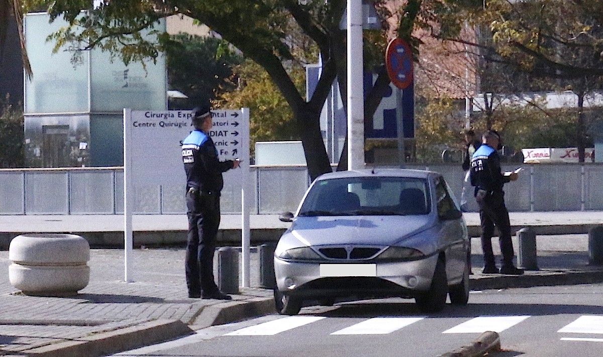 Dos agents de la Policia Municipal multant un vehicle mal estacionat