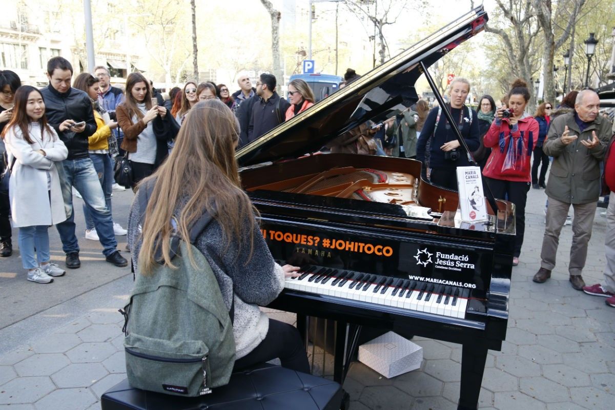 Una noia toca el piano davant de la Casa Batlló al passeig de Gràcia de Barcelona
