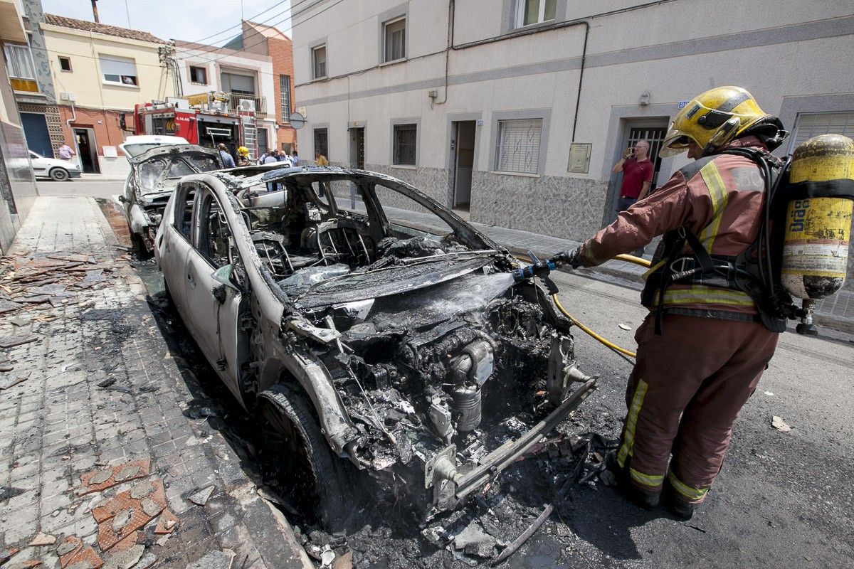 Un bomber apagant el foc que ha afectat els dos cotxes