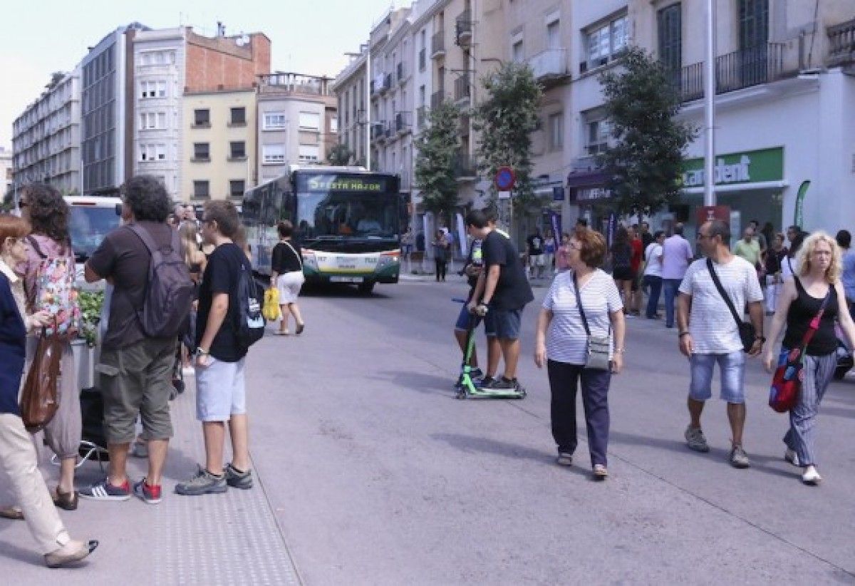 Un autobús circulant entre la gent pel Passeig per Festa Major