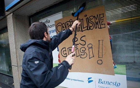Un piquet enganxat un cartell als videres d'una oficina bancària del carrer Verdaguer.