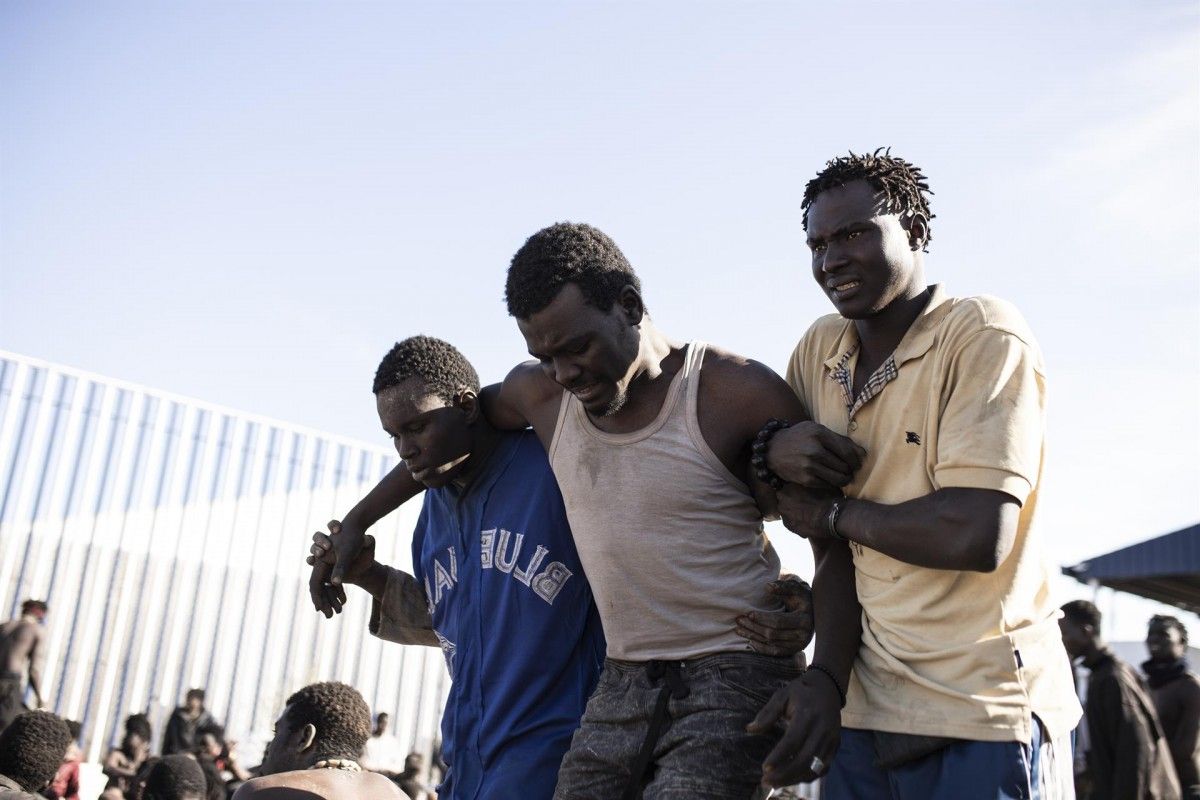 Un grup de migrants a la tanca de Melilla, amb un ferit