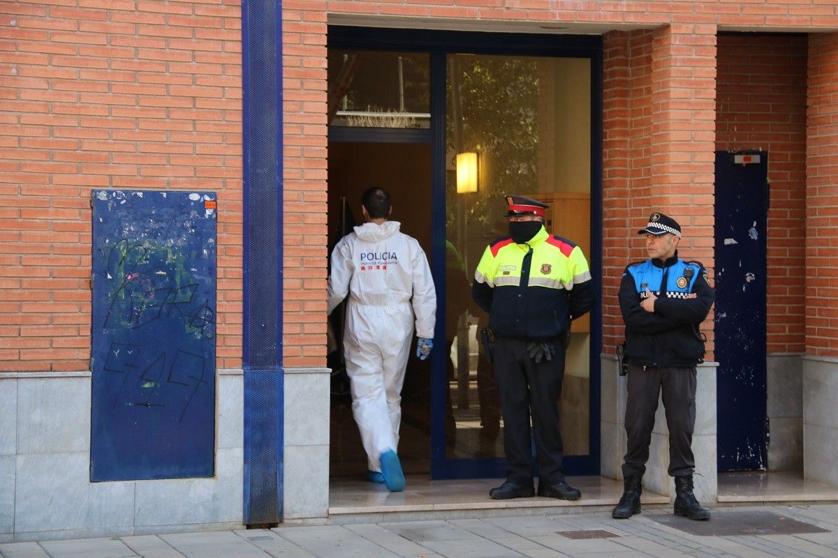 Un agent de la divisió d'investigació criminal dels Mossos accedint a l'edifici d'Esplugues on ha tingut lloc el crim.