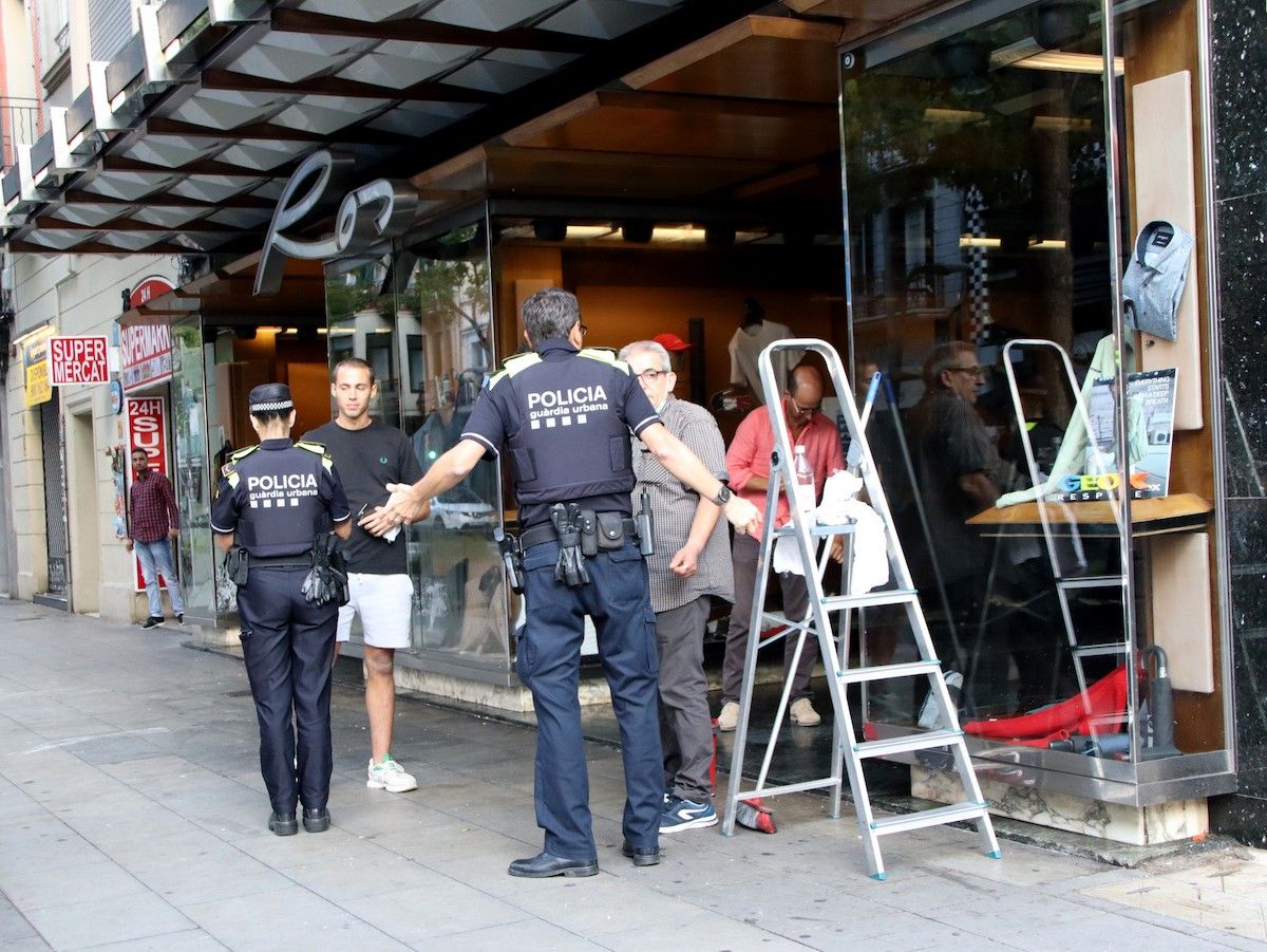 Agents de la Guàrdia Urbana conversen amb comerciants afectats per destrosses al carrer Creu Coberta.