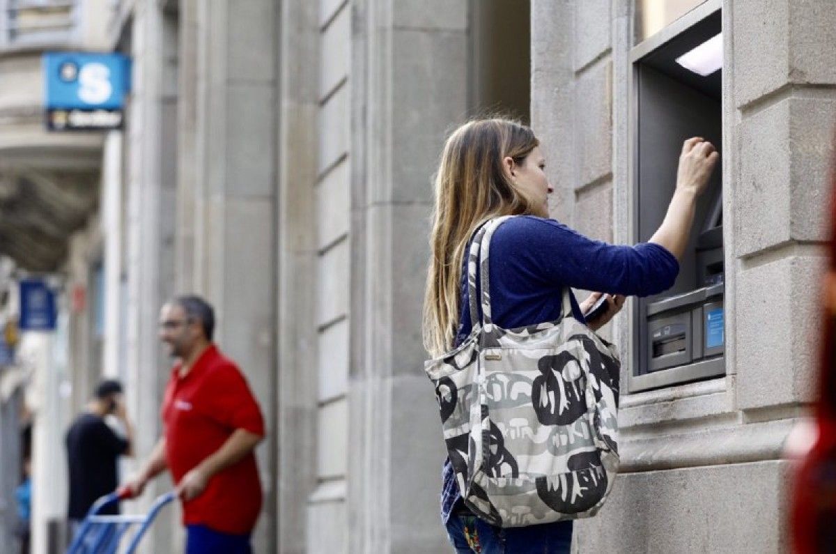 Una usuària traient diners del caixer que el banc té a la plaça Sant Roc 