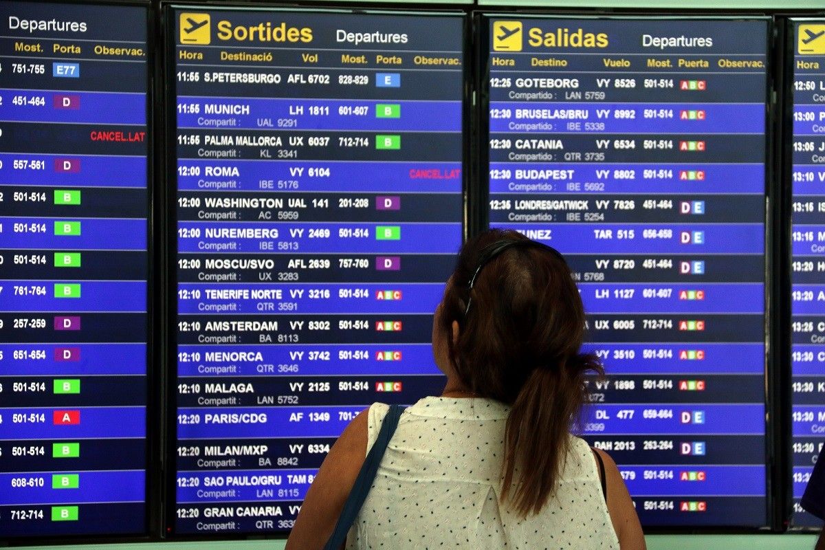 Una usuària de l'aeroport del Prat observant la pantalla de vols.