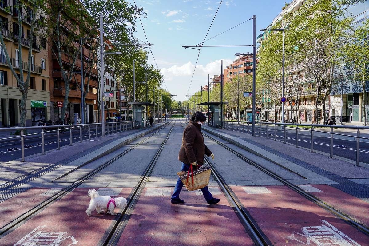 Una vianant passeja el gos per una Barcelona confinada. 