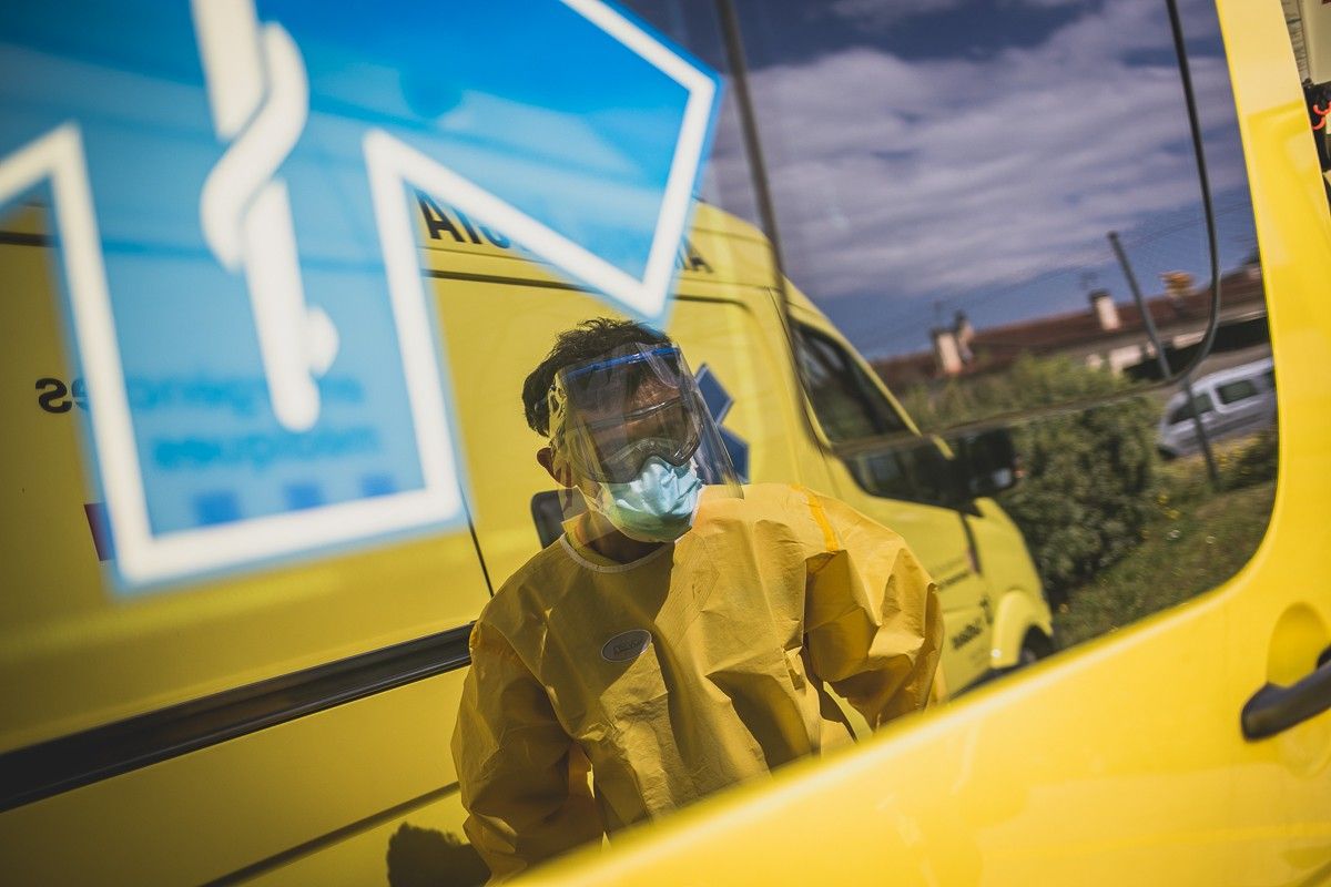 Un sanitari protegit, al costat d'una ambulància a l'Hospital d'Olot. 