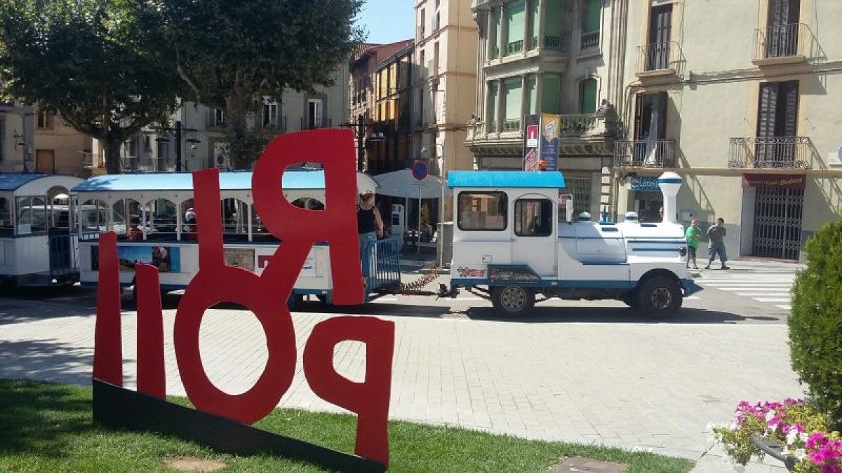 El trenet turístic de Ripoll sortint de la plaça de l'Abat Oliba, davant del Monestir