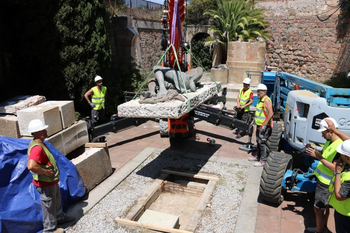 Un grup d'operaris treu l'àngel del Monument als caiguts del Castell de Montjuïc