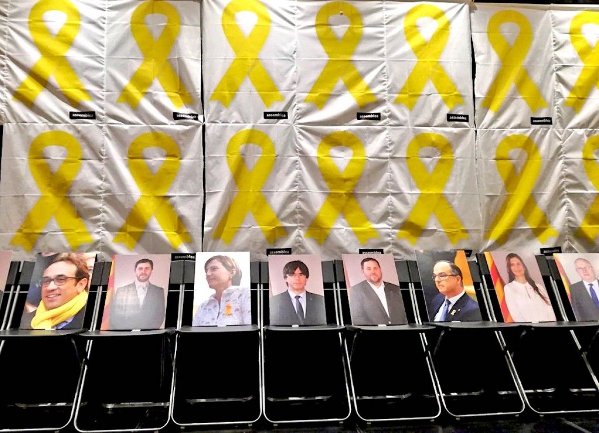 Cadires buides amb les fotos dels polítics catalans a la presó a l'exili