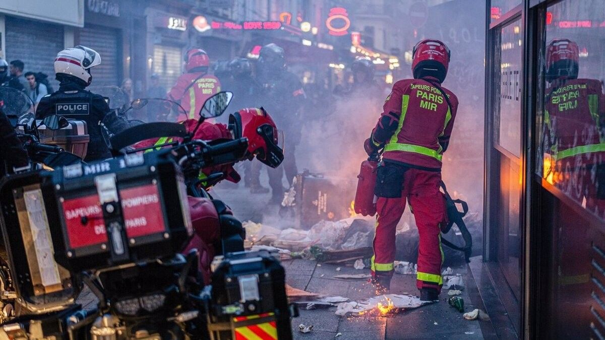 Un agent de policia i un bomber treballen en els aldarulls a París