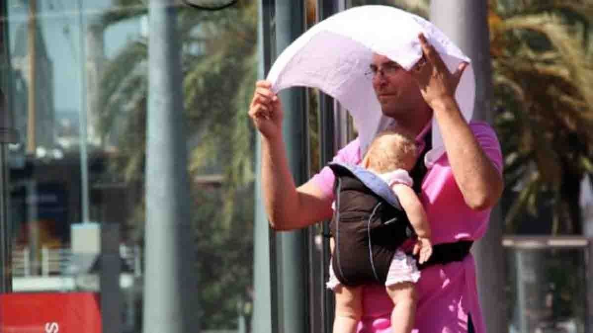 Un home protegint un nadó del sol