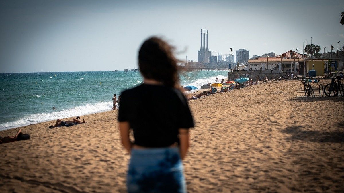 L'Ainhoa, d'esquenes, amb el xiringuito Kailua de fons