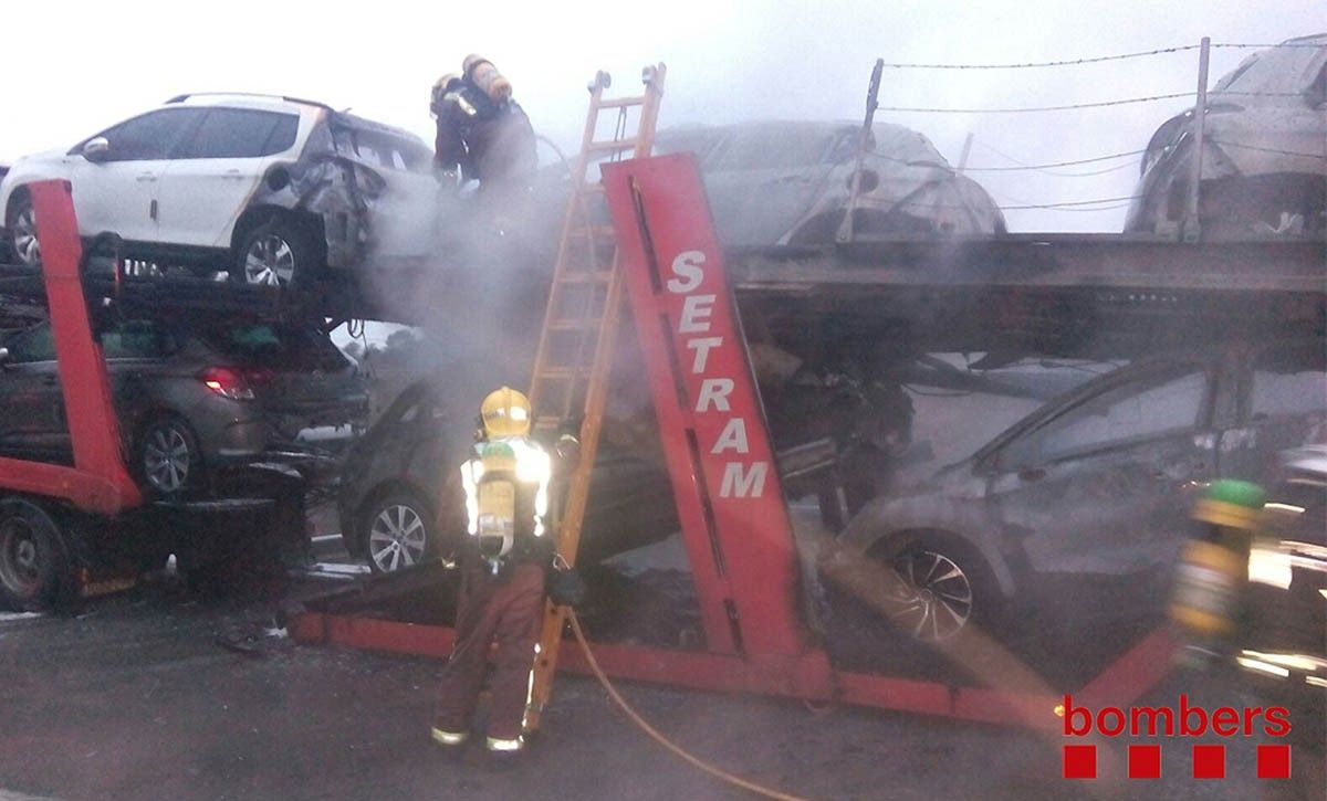 Un efectiu dels Bombers revisa el camió que transportava cotxes incendiat